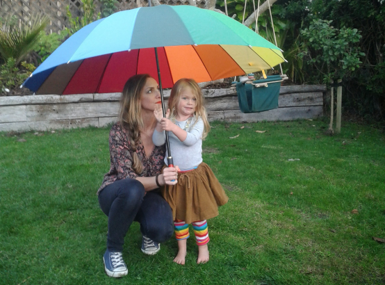 Kate Collins and child under a rainbow umbrella 